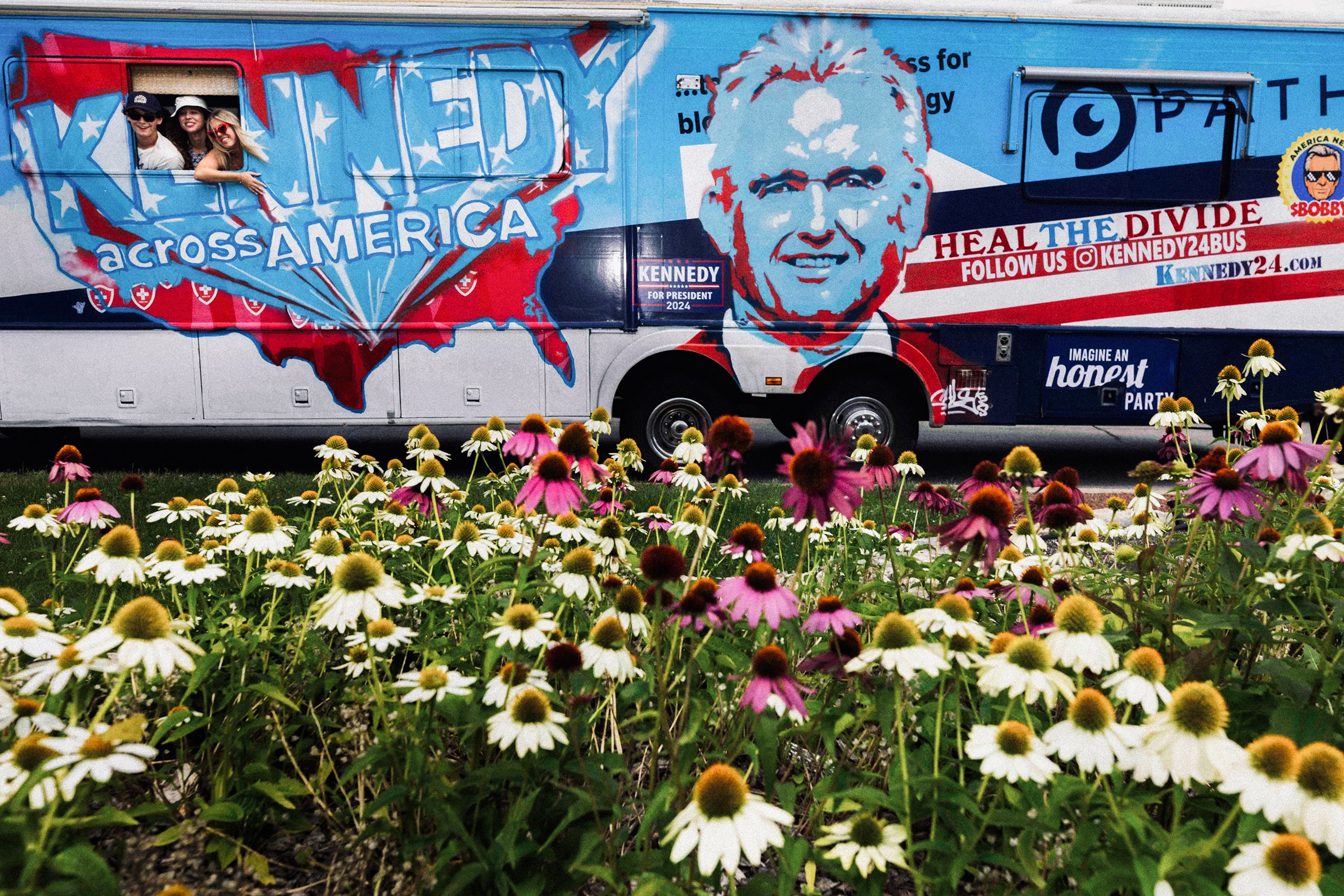 A photo of people leaning out of a Robert F. Kennedy Jr. campaign bus outside of the 2024 Republican National Convention.