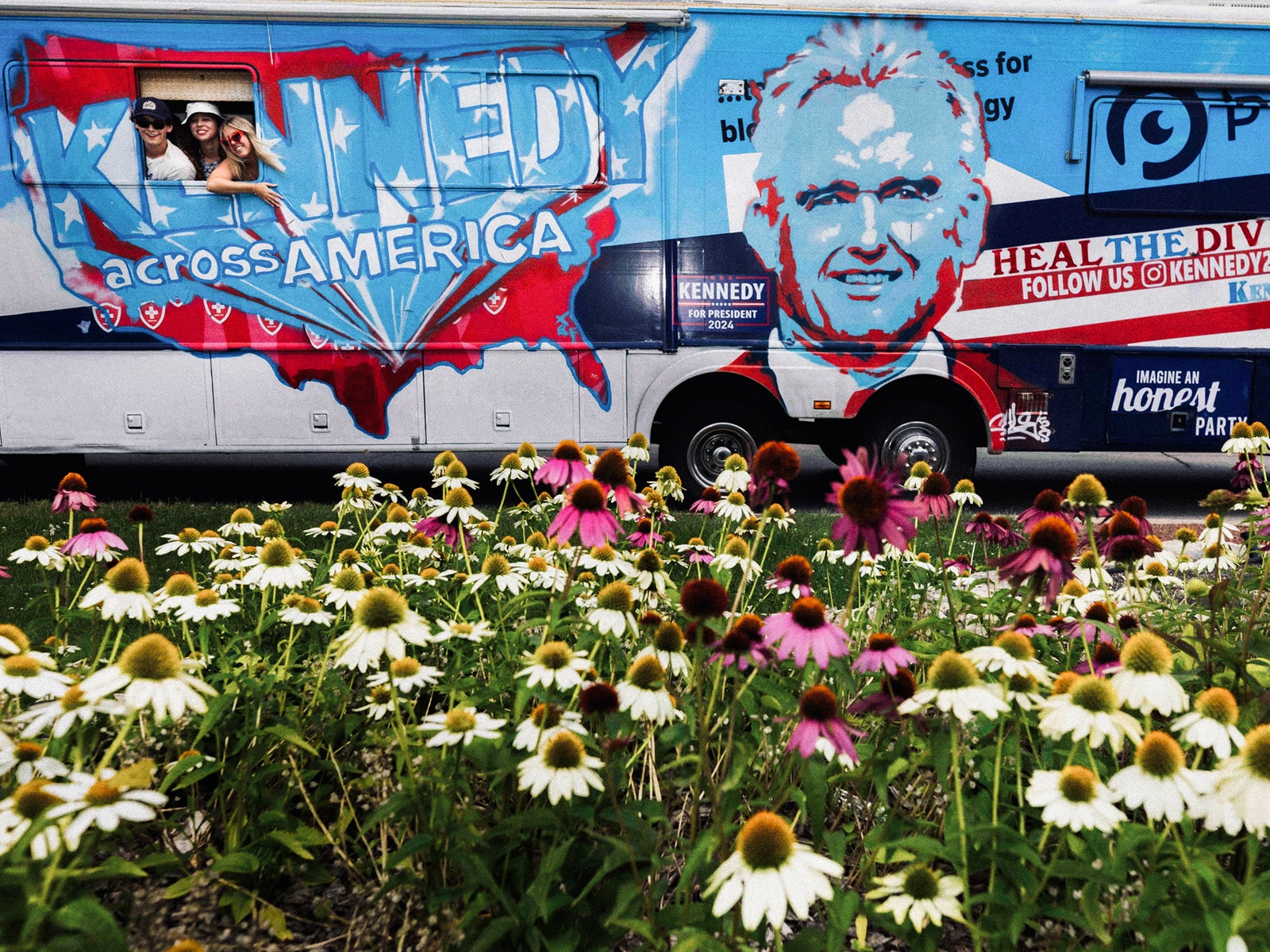 A photo of people leaning out of a Robert F. Kennedy Jr. campaign bus outside of the 2024 Republican National Convention.