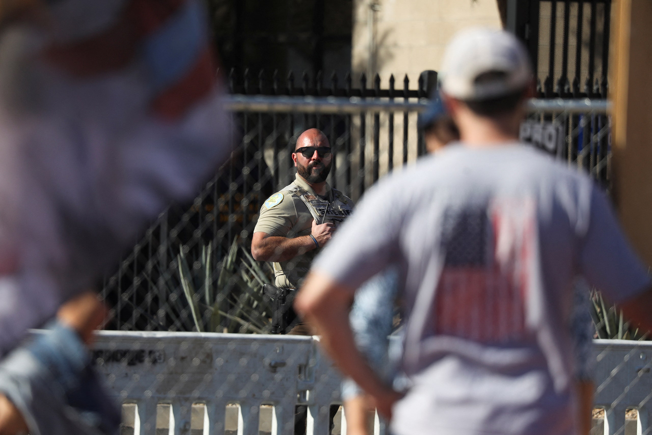 A law enforcement officer keeps watch on demonstrators outside the perimeter of a temporary security fence as they...